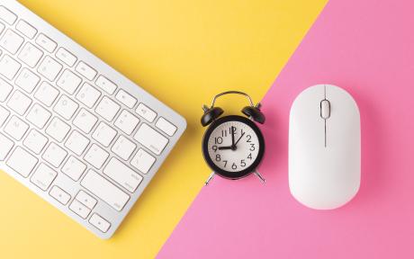 clavier, souris blanche et réveil sur fond jaune et rose