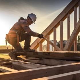 ouvrier avec casque et charpente bois d'une maison avec coucher de soleil