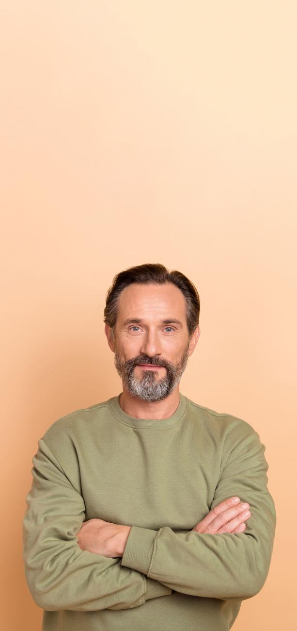 homme rassurant avec barbe, bras croisés, sur fond orange vertical