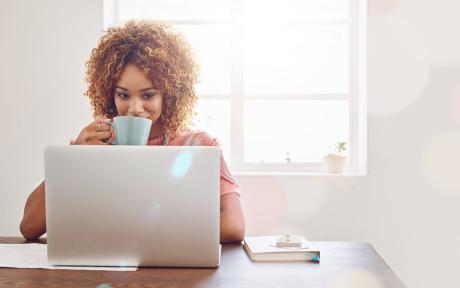 femme buvant son café devant un ordinateur, travaillant à distance