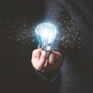 main tenant une ampoule lumineuse sur fond noir