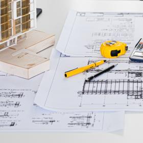 plan d'architecte, casque jaune, ordinateur et maquette de bâtiment