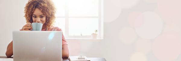 femme buvant son café devant un ordinateur, travaillant à distance